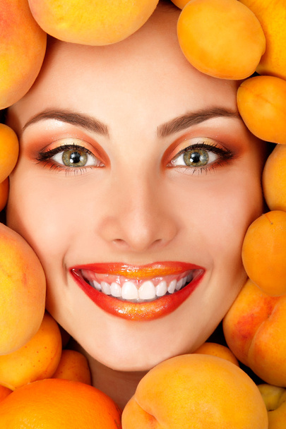 Summer portrait of young healty smiling attractive woman with ripe big fresh peaches and apricots - Фото, зображення