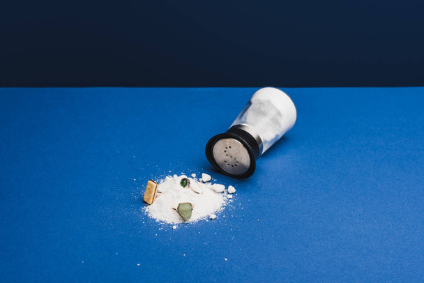 Schmuckringe mit Edelsteinen auf Salz per Salzstreuer auf klassisch blauer Oberfläche - Foto, Bild