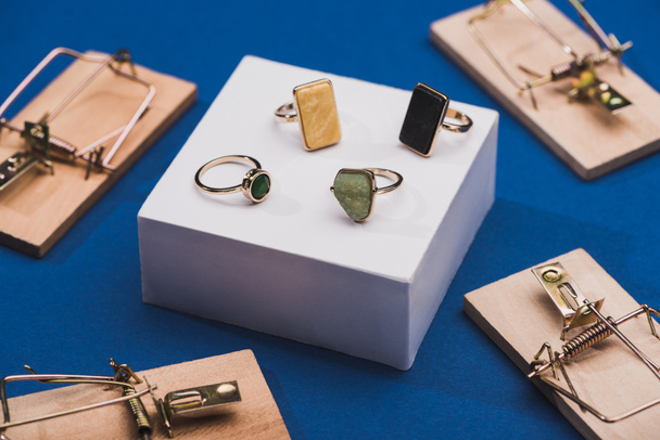 Close-up vista de anéis de jóias em branco stand by mouse armadilhas no fundo azul
 - Foto, Imagem