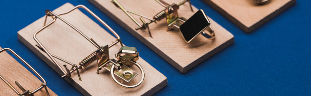 Pierścienie biżuterii w drewnianych pułapkach na myszy na niebieskiej powierzchni, zdjęcie panoramiczne - Zdjęcie, obraz