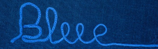 Top view of word blue from thread on blue textile, panoramic shot - Photo, Image