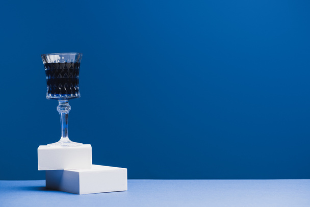 Бокал вина с голубой жидкостью на блоках на классическом голубом фоне
 - Фото, изображение