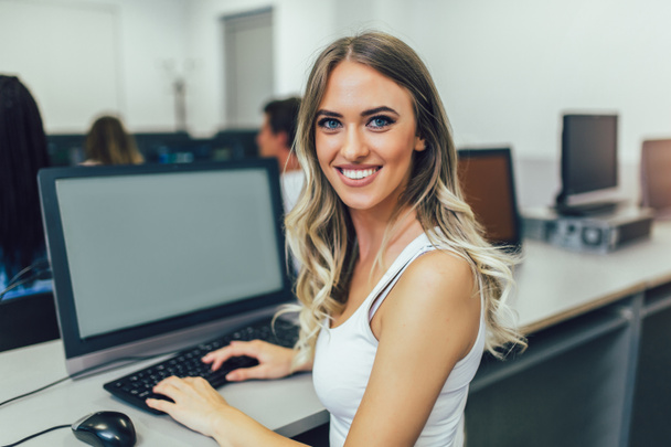 Jeune belle fille travaillant sur un ordinateur dans une salle de classe
 - Photo, image