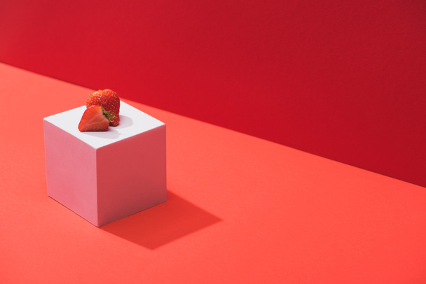 fresh ripe strawberry on cube on red background - 写真・画像