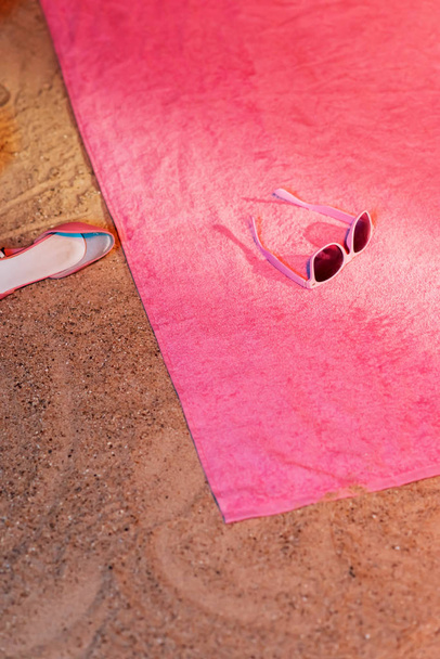 Vintage Damenschuh im Sand neben rosa Handtuch mit Sonnenbrille o - Foto, Bild