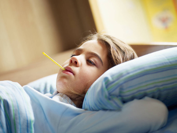 girl taking temperature in bed. Copy space - Zdjęcie, obraz