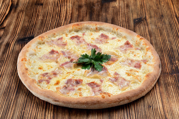 heiße italienische Pizza mit geschmolzenem Käse und Speckstreifen auf Holzgrund  - Foto, Bild