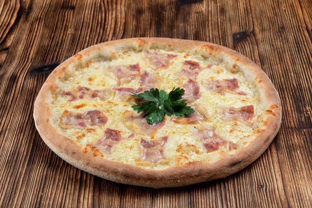 Pizza italiana caliente con queso derretido y tiras de tocino sobre fondo de madera
  - Foto, imagen
