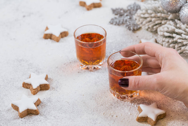 Woman holds a glass of whiskey, brandy or liquor. Cookies, drink - Foto, Imagen