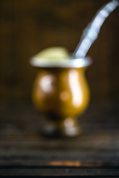 unfocused mate, image for background. A pump, ground yerba mate and boiling water. Chimarrão isolated on wooden background. Copy space - Foto, imagen
