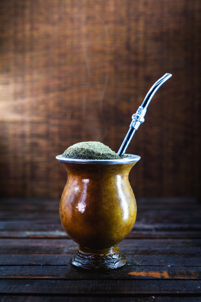 Gaucho yerba mate tea, the chimarrão, a typical Brazilian drink, traditionally in a bombilla stick cuiade gourd against a wooden background. Rio Grande do Sul, favorite drink of the gauchos. - Foto, afbeelding