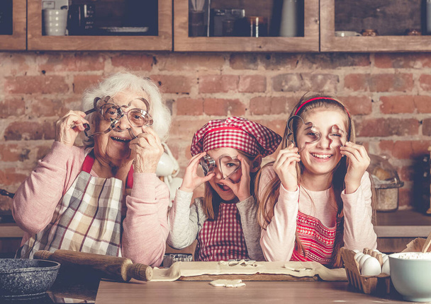 Granny with granddaughters looking at camera through cookie cutters - Zdjęcie, obraz