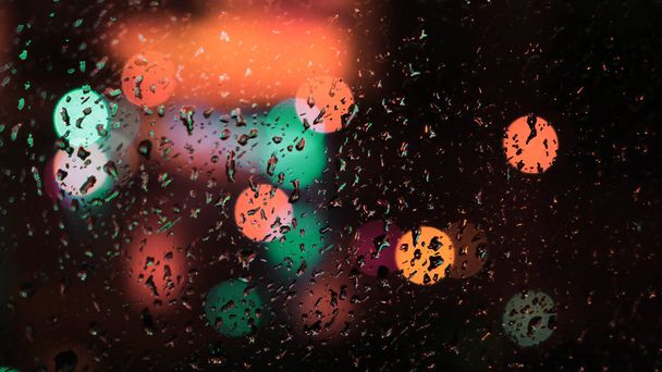 abstrakter Hintergrund mit verschwommenen Taschenlampen vor dem Fenster. Konzept. Farbige Laternen hinter dem Glas - Foto, Bild