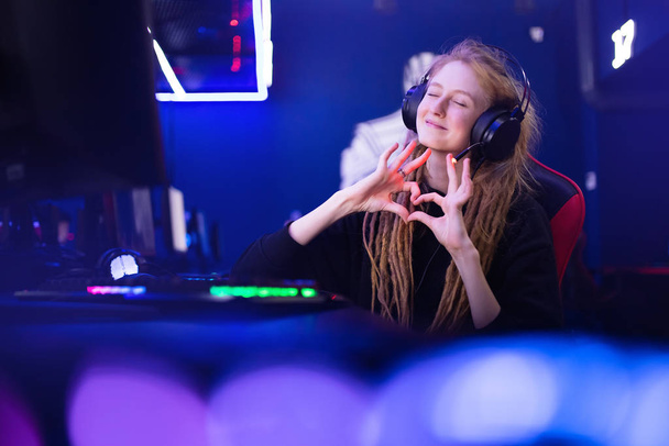 Streamer krásná dívka ukazuje srdeční znamení s rukama profesionální hráč hraje online hry počítač, neon barva - Fotografie, Obrázek