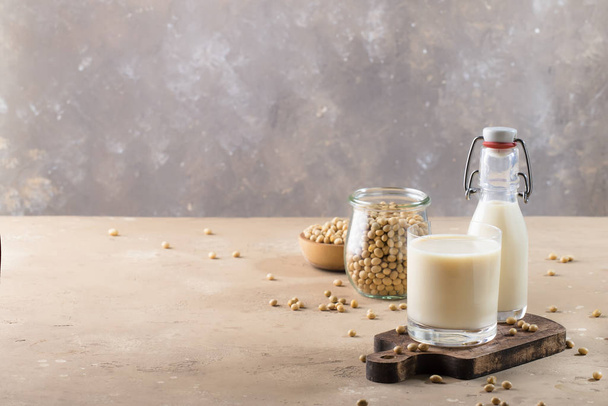 Soy milk and soy bean on gray table. Non-dairy milk concept. Vegan drink. Copy space - Fotó, kép