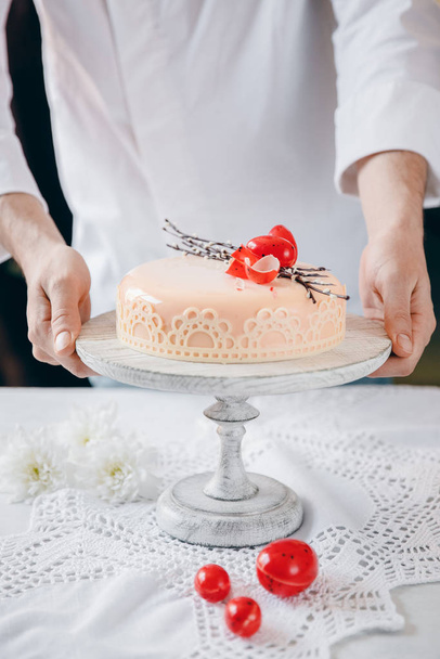 Male chef puts Easter cake kulich with chocolate eggs and willow on table - Photo, Image