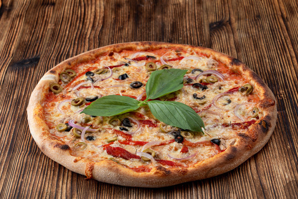 Włoska pizza z czerwoną cebulą, czarno-zielone oliwki, topiony ser i ketchup na rustykalnym tle teksturowanym - Zdjęcie, obraz