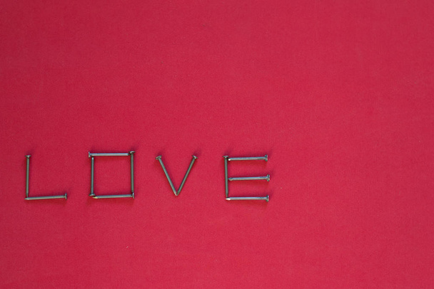 The inscription LOVE made of nails. Metallic inscription for the bottom of Valentines Day. Concept of love. Space for text - Fotografie, Obrázek