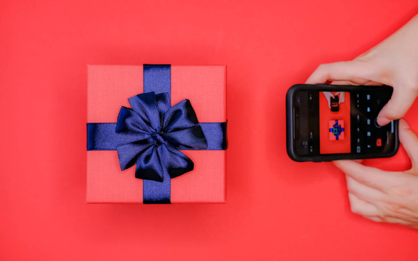 Cellphone in hands and gift box. - 写真・画像
