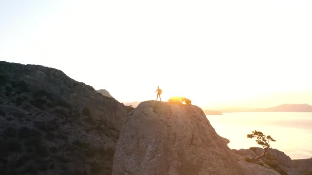 Luchtfoto van de berg Karaul-Oba en een man met een rugzak die naar de top klom. De man wandelde en klom een van de toppen van de berg tegen de achtergrond van zonsondergang en de Zwarte Zee in de Krim - Video