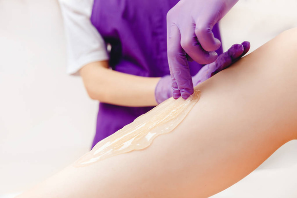 ontharing procedure suiker op been van vrouw met suikerpasta in salon - Foto, afbeelding