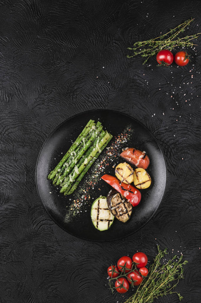 Grilled vegetables on a black plate. Asparagus, bell pepper, zuc - Foto, Imagen