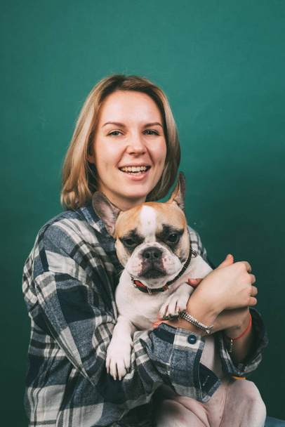 junges Mädchen und umarmt eine französische Bulldogge auf grünem Hintergrund - Foto, Bild