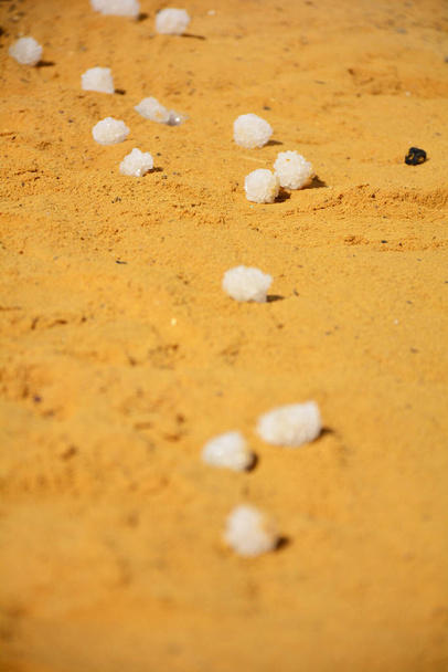 Кристаллические шарики соли Мертвого моря на желто-оранжевом пляже
 - Фото, изображение