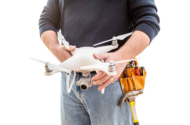 Trabalhador de construção e piloto de drones com cinto de ferramentas segurando quadcopter drone isolado em fundo branco
 - Foto, Imagem