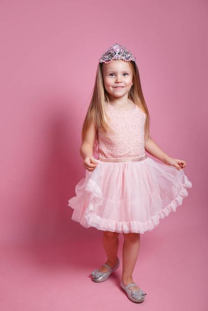 Funny little girl with long blond hair in a tulle skirt and princess sparkling crown - Fotoğraf, Görsel