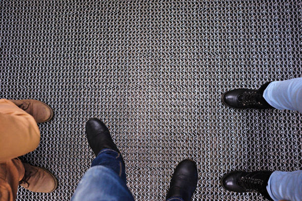Trois personnes debout sur le sol métallique. Vue de haut en bas. Jeans et bottes
. - Photo, image