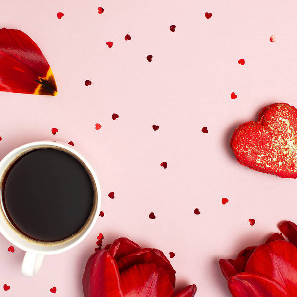 Rode tulpen, rood hartvormige Gift Box, kopje koffie, Macaron taart, confetti op pastel roze achtergrond Top View platte lag. Moederdag Valentines Day verjaardag vakantie achtergrond. Mooie wenskaart - Foto, afbeelding