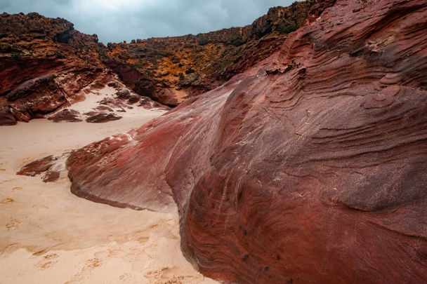 Rocce oceaniche rosse sulla spiaggia sotto la luce del tempo nuvoloso. Praia da Bordeira. Carrapareira, Costa dell'Algarve in Portogallo, Oceano Atlantico
 - Foto, immagini