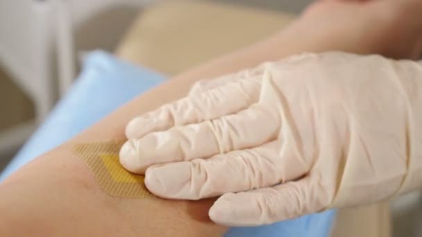 Εξετάσεις αίματος στο Ιατρικό Εργαστήριο. Νοσοκόμα τυλίγει το γυναικείο χέρι με στείρο επίδεσμο μετά τη λήψη φλεβικού δείγματος αίματος. 4 k πλάνα - Πλάνα, βίντεο