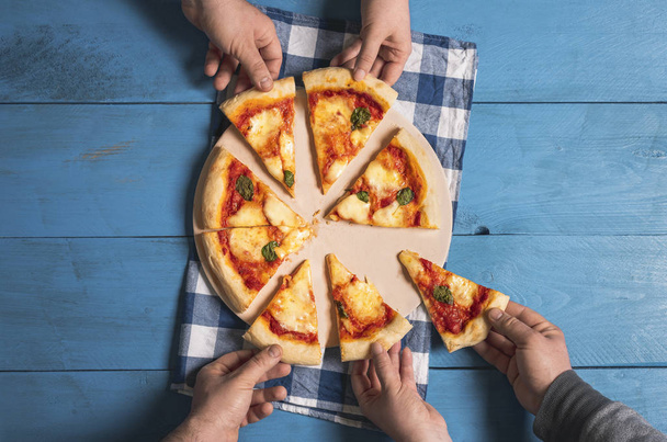 Pizzasiivuja. Ihmiset ottavat pizzaa margherita viipaleita
 - Valokuva, kuva