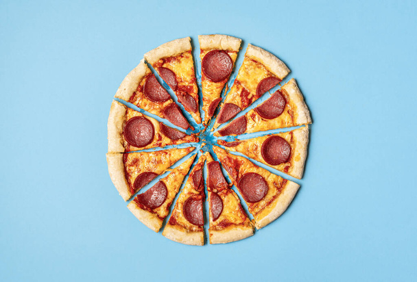 Pizza pepperoni tranchée sur fond bleu. Tranches de salami pizza
 - Photo, image