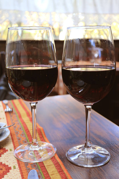 Κάθετη εικόνα από δύο ποτήρια κόκκινο κρασί στο τραπέζι στο εστιατόριο - Φωτογραφία, εικόνα