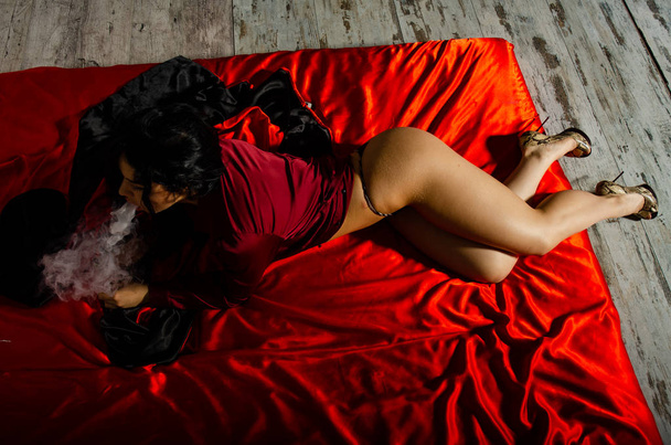 Сексуальна молода жінка в чорній білизні парі в спальні. Красива брюнетка жінка курить
 - Фото, зображення