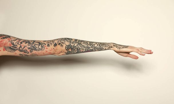 Woman with colorful tattoos on arm against white background, closeup - Фото, зображення