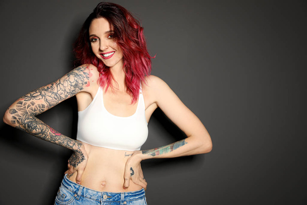 Beautiful woman with tattoos on body against black background - Фото, зображення