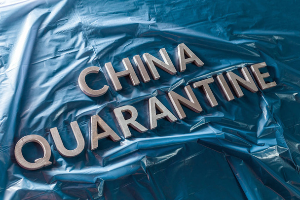 Çin karantinası kelimesi, buruşmuş mavi plastik film üzerinde gümüş harflerle köşegen perspektifte sıralanmıştır. - Fotoğraf, Görsel