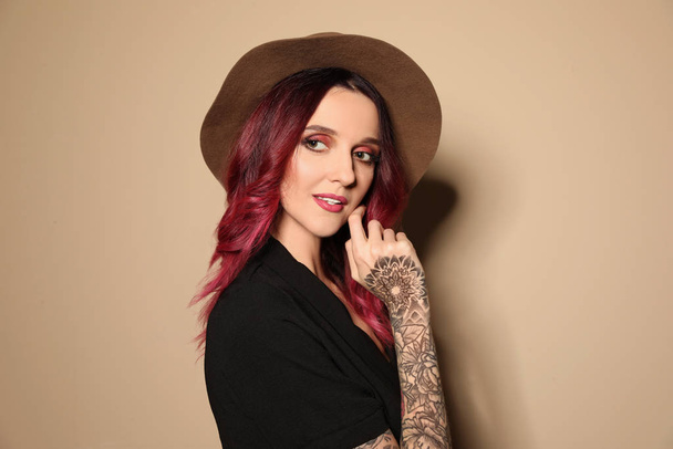 Beautiful woman with tattoos on arms against beige background - Valokuva, kuva
