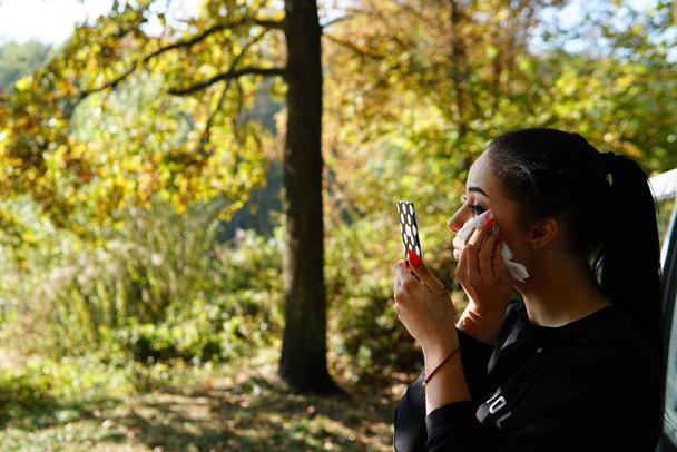 dziewczyna robi makijaż w pobliżu samochodu w lesie - Zdjęcie, obraz