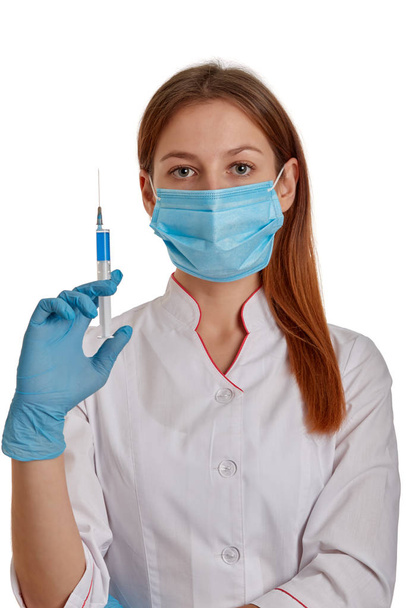 Крупним планом фото жінки-лікаря в білому пальто. Лікар тримає в руках шприц з ліками. Доктор у білому пальто на білому тлі
. - Фото, зображення