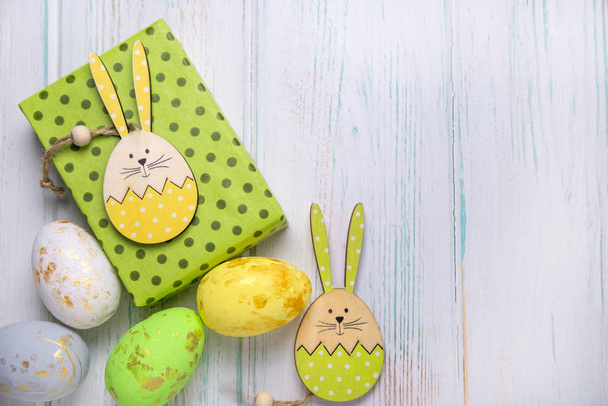 Fondo de madera para una tarjeta de Pascua con una caja de regalo, huevos y un conejo con un lugar para copiar espacio. Feliz Pascua.
 - Foto, Imagen