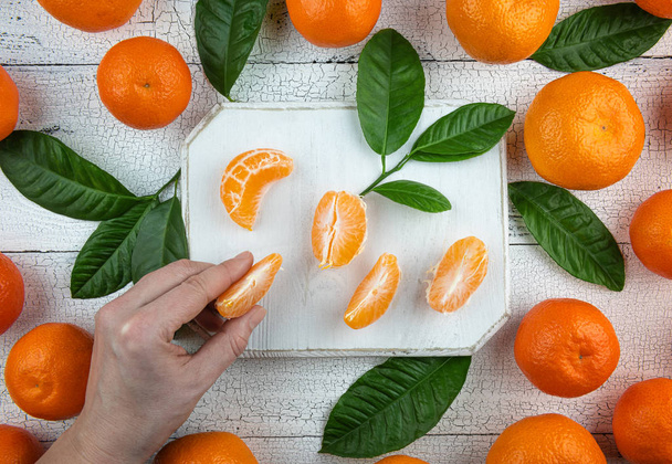 Mujer toma segmentos de mandarina de tabla de cortar
 - Foto, imagen