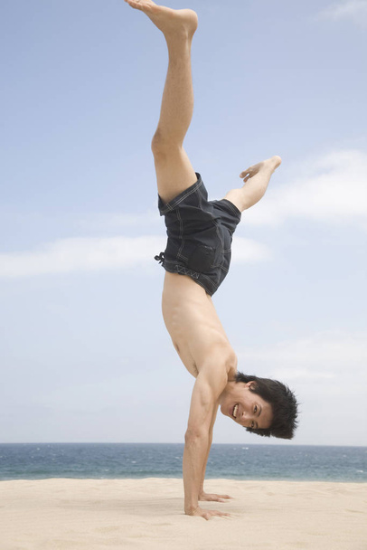 Japanese man doing gymnastics on a beach - Foto, Imagem