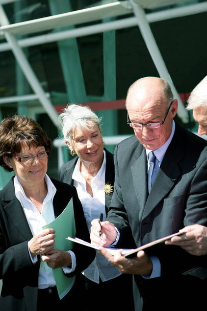 Portrait of a group of seniors read the documents to a modern building - Fotó, kép