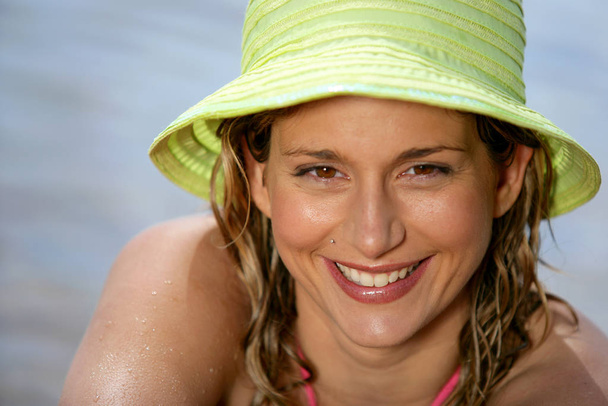 χαμογελαστή γυναίκα με καπέλο μπροστά στη θάλασσα - Φωτογραφία, εικόνα