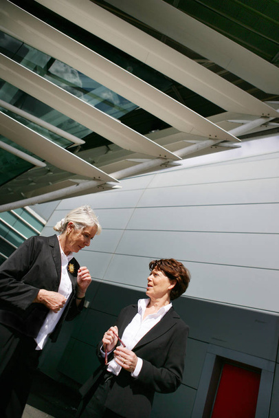 Пожилые женщины в деловом костюме смотрят перед обсуждением современного здания - Фото, изображение